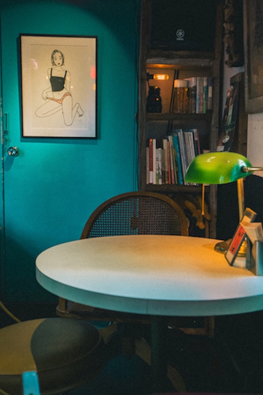 GOBLIN.池尻大橋BAR店｜ダークトーンの本棚とターコイズブルーの壁紙がマッチした一角