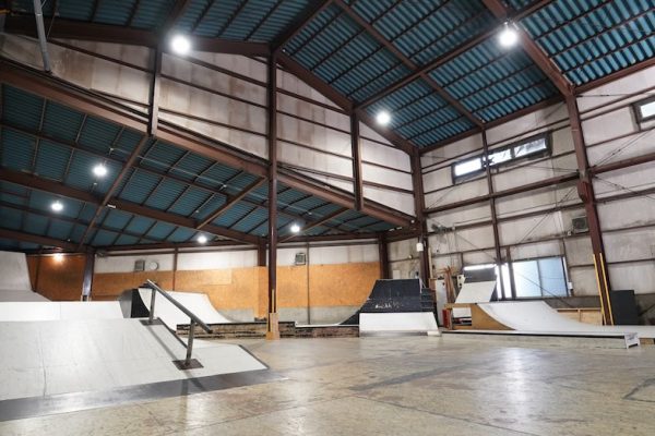 鉄骨フレームと高い天井が特徴の倉庫空間にある屋内型スケートパーク