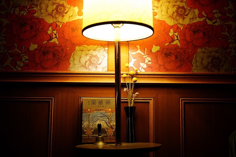 BAR TAMBI｜暖色の光が花柄の壁紙を柔らかく照らし、バーの落ち着いた雰囲気を伝えます