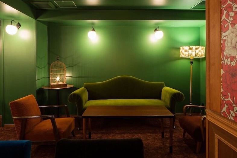 BAR TAMBI｜壁面照明に照らされたグリーンのソファ席は落ち着いたラウンジシーンやインタビューシーンの撮影に
