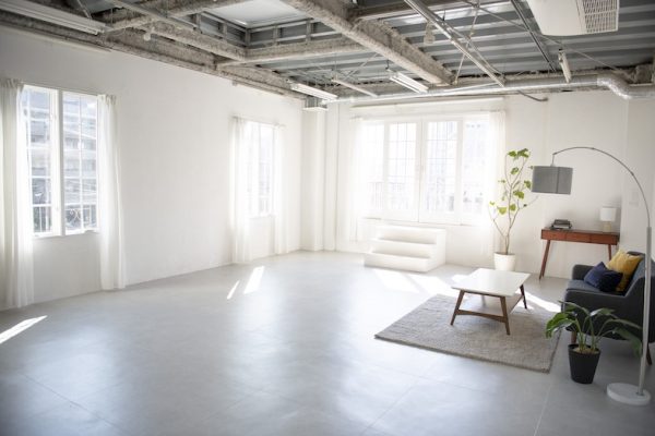 光が降り注ぐ大きな窓と白壁に囲まれた広々リビング空間