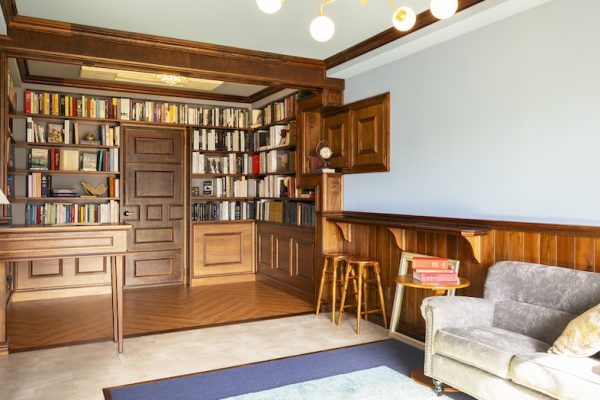 【3F Archive】書庫に繋がるバー風カウンター＆ソファスペース。木の質感と落ち着いた配色でムードが出て、対談・インタビュー・シネマティックな動画撮影に最適です