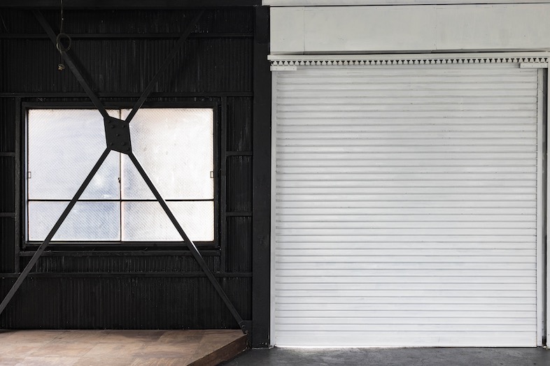 EARTHY BLUE STUDIO｜黒く塗られた壁と白いシャッターのコントラストはシンプルながら印象的な背景