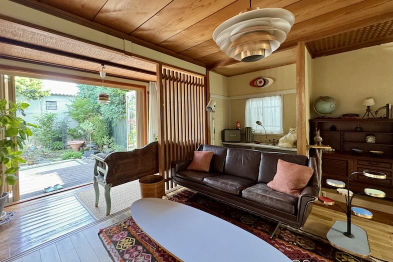 アルバートハウス練馬｜【1階 】緑鮮やかな庭の植栽を望むヴィンテージソファが置かれたリビング