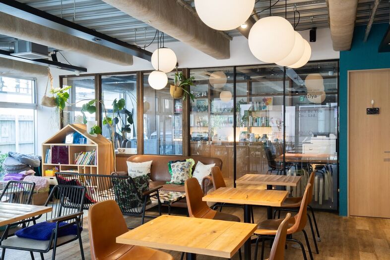 GOBLIN.参宮橋CAFE店｜ガラス仕切りの奥に事務エリアが覗くカフェ席は奥行きある構図