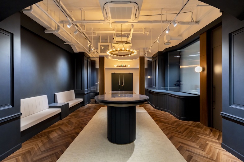 九段下 Design Office｜重厚な黒壁、ヘリンボーン床、豪華な照明、中央のラウンドテーブルが印象的なエグゼクティブ仕様の空間