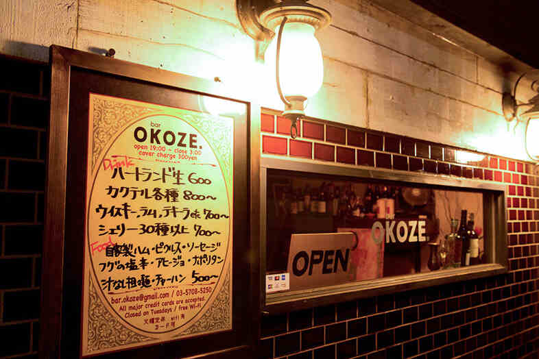 bar OKOZE.｜料金メニューが掲げられた入口周辺、看板・案内表示を絡めた店構えの撮影に