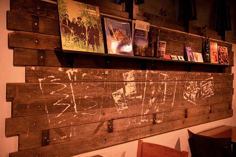 bar OKOZE.｜古書や雑貨を飾った木壁の一角、小物を活かしたスタイリング撮影のアクセントに