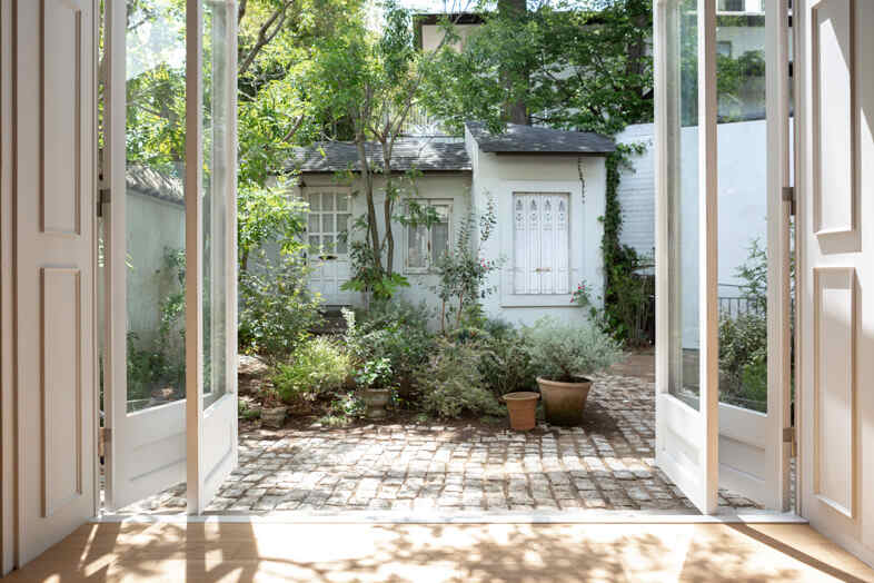 mimosa house︎ リゾート｜【1F】大きく開く扉から石畳の庭を望む屋内外の構図
