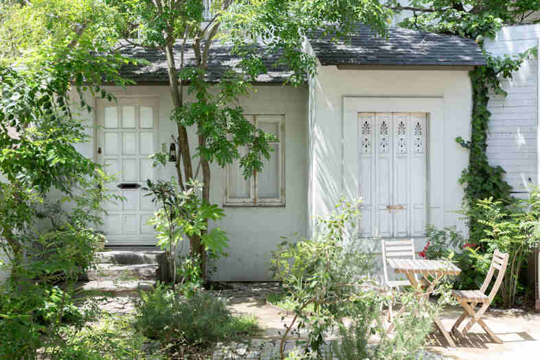 mimosa house︎ リゾート｜【庭】木々に囲まれた白い外壁と小屋を望むガーデン