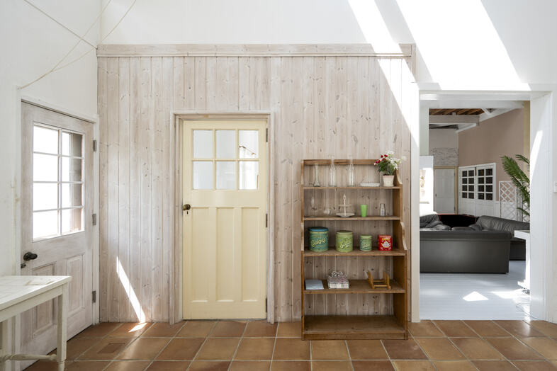 Greige House Studio by KIC｜【ダイニングキッチン】板張りの通路の先に別の部屋が続き、空間の奥行きと広がりを感じさせる