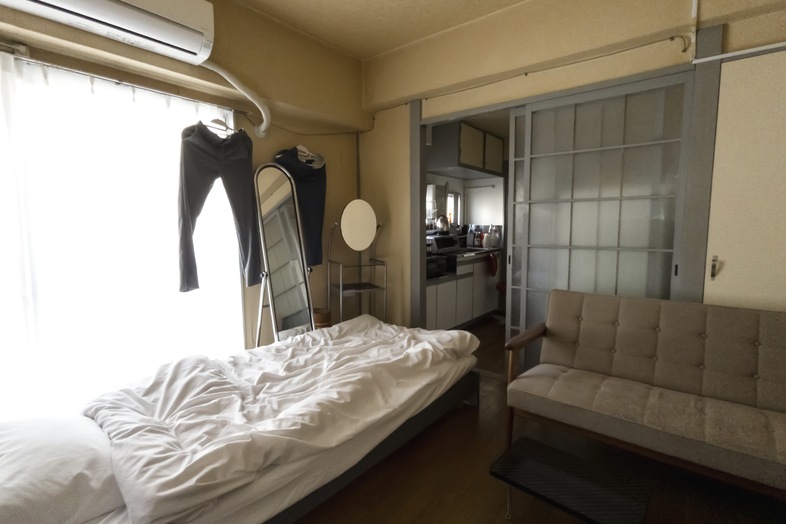 築古マンション｜【308 6畳ひとり暮らし】窓際のベッドとソファでくつろぐ場面に
