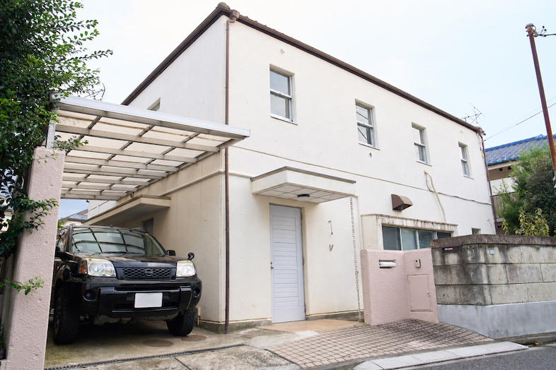 studio cork｜白い外壁と屋根付き駐車スペースを備えた建物